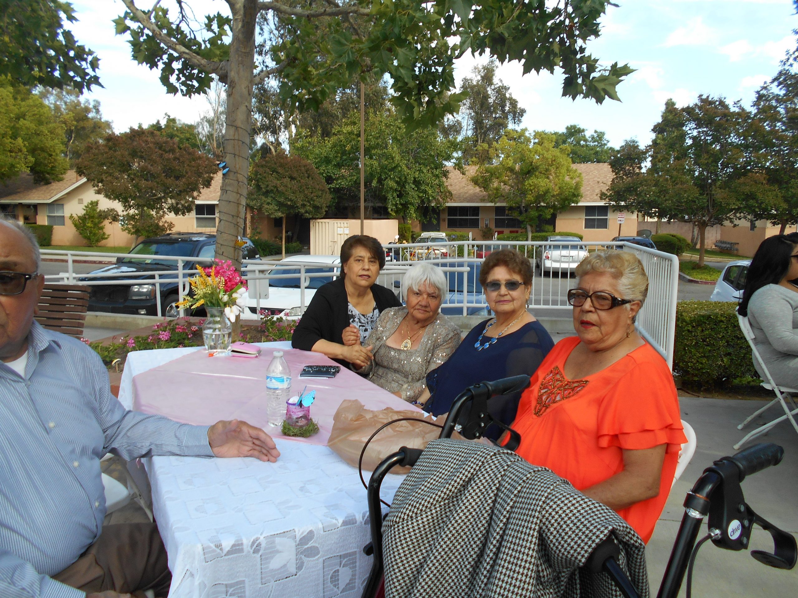 Photo of five residents, four women and one man, sitting outside at an event at Cambridge Gardens senior housing community.