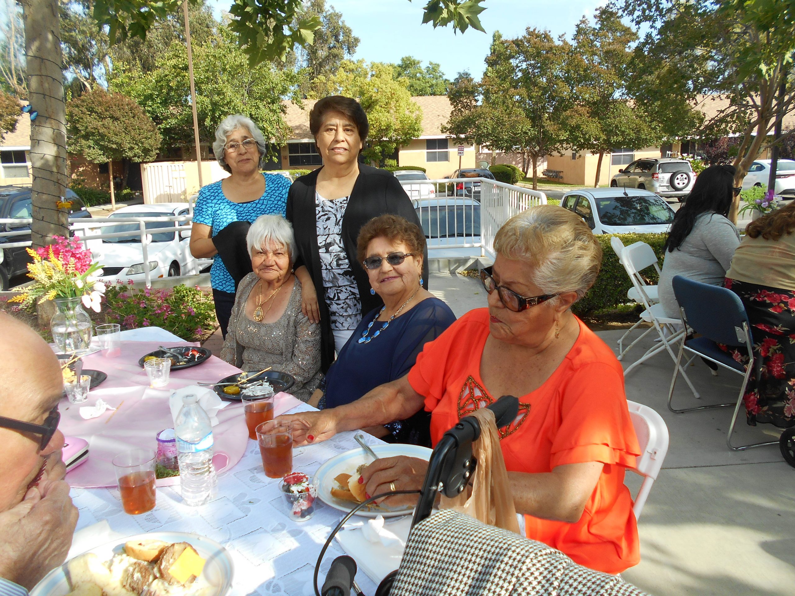 Photo of residents sitting outside at an event at Cambridge Gardens senior housing community.