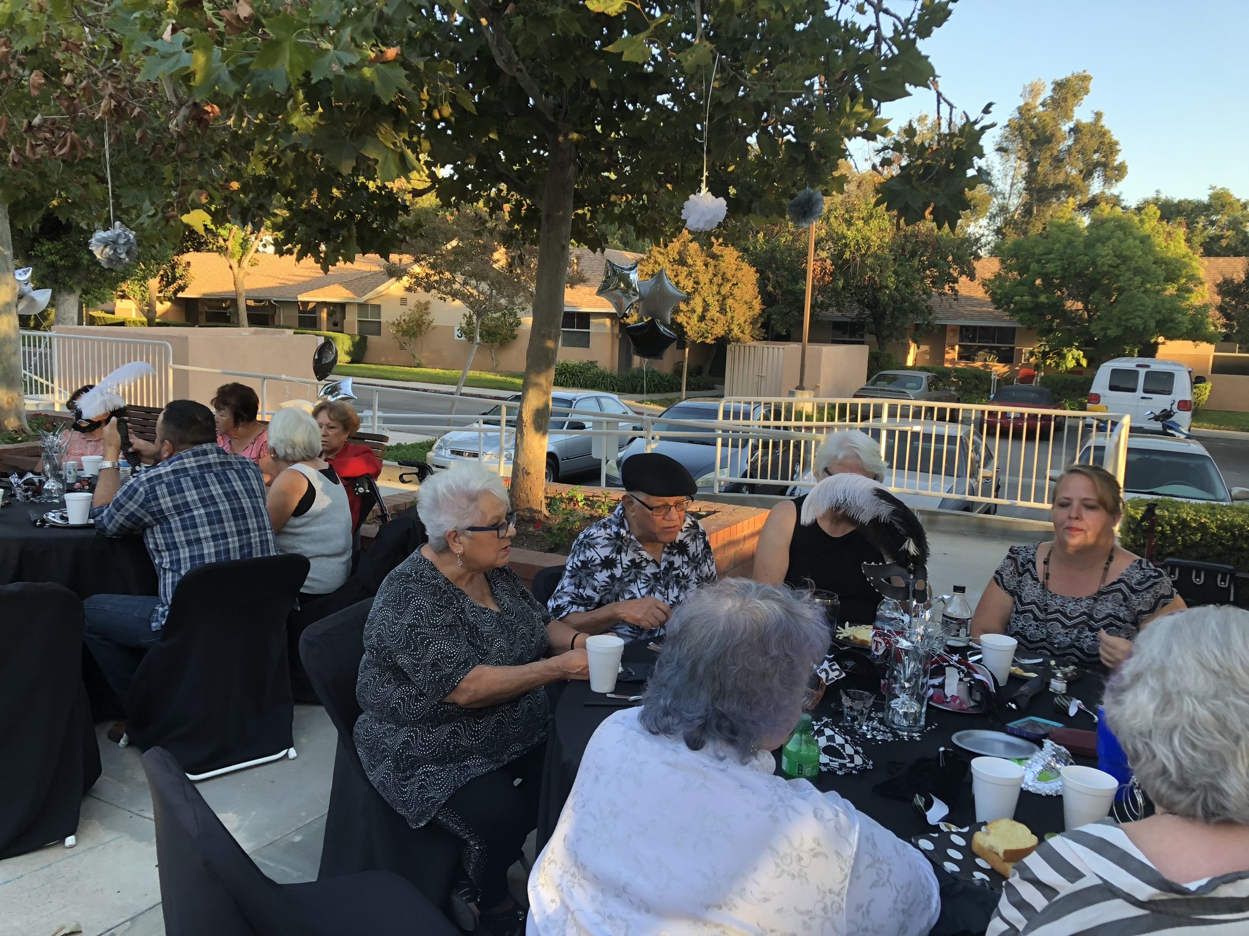 Photo of residents and family sitting outside at an event at Cambridge Gardens senior housing community.