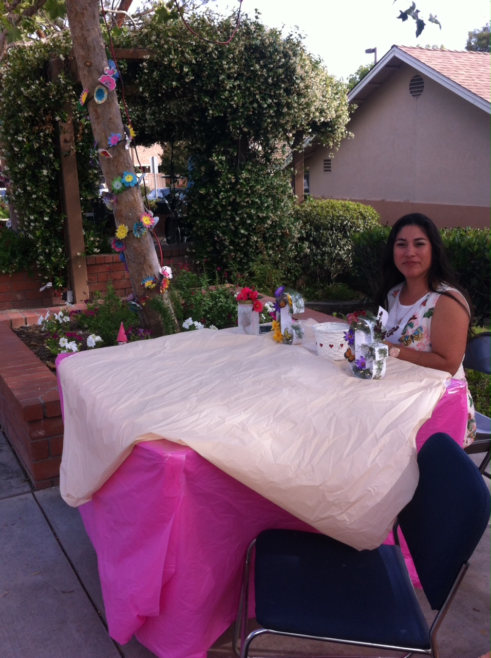 A woman sitting at a table covered in pink fabric at the Cambridge Gardens senior housing community.