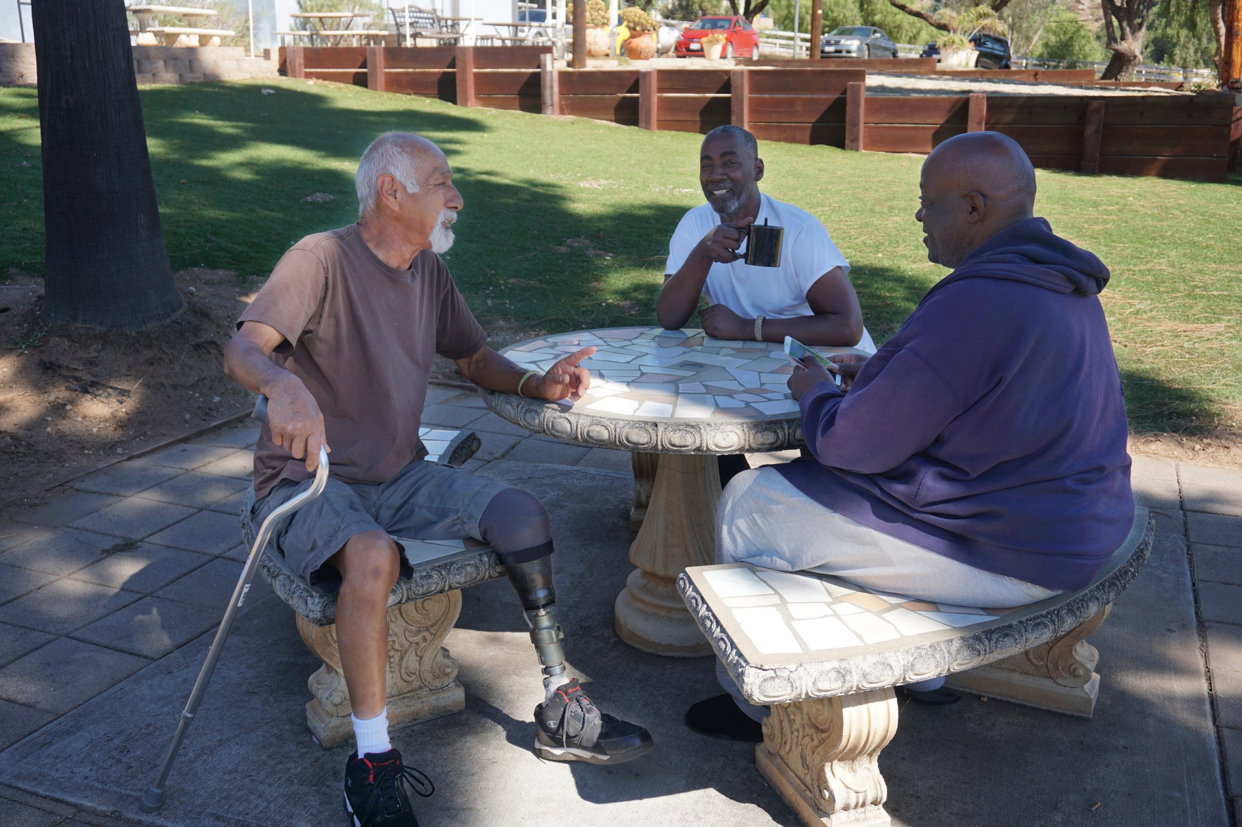 Three male veterans sitting outside at a Volunteers of America Southwest veteran housing community. Veteran housing communities provides both housing and services for veterans.