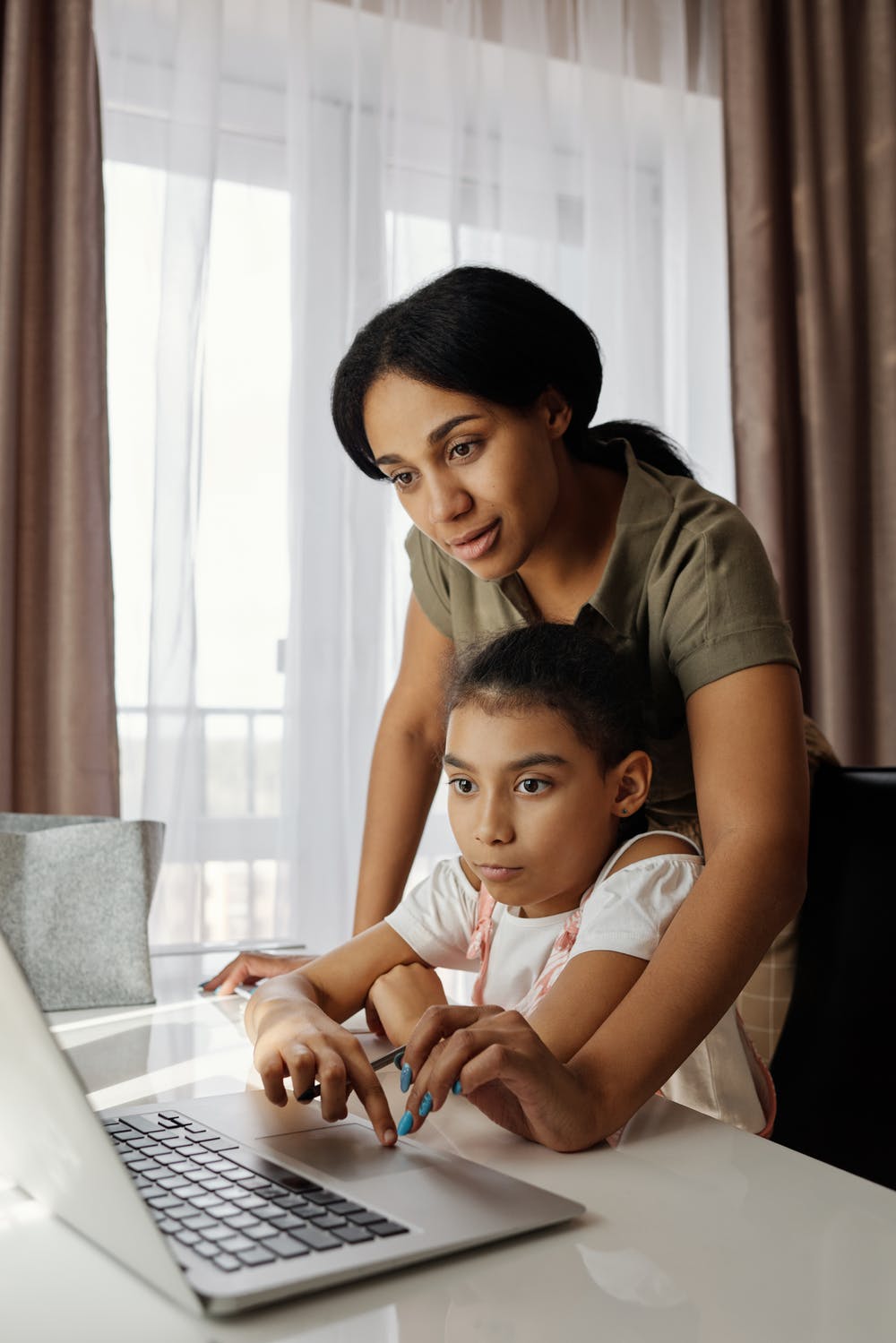 mom helping daughter homeschool on chromebook